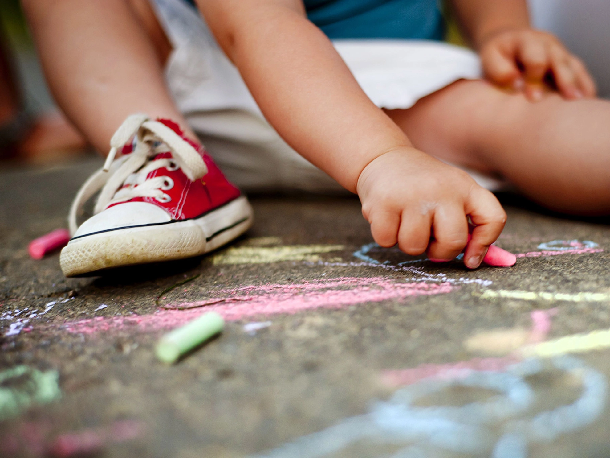 Kind malt mit Kreide auf dem Asphalt