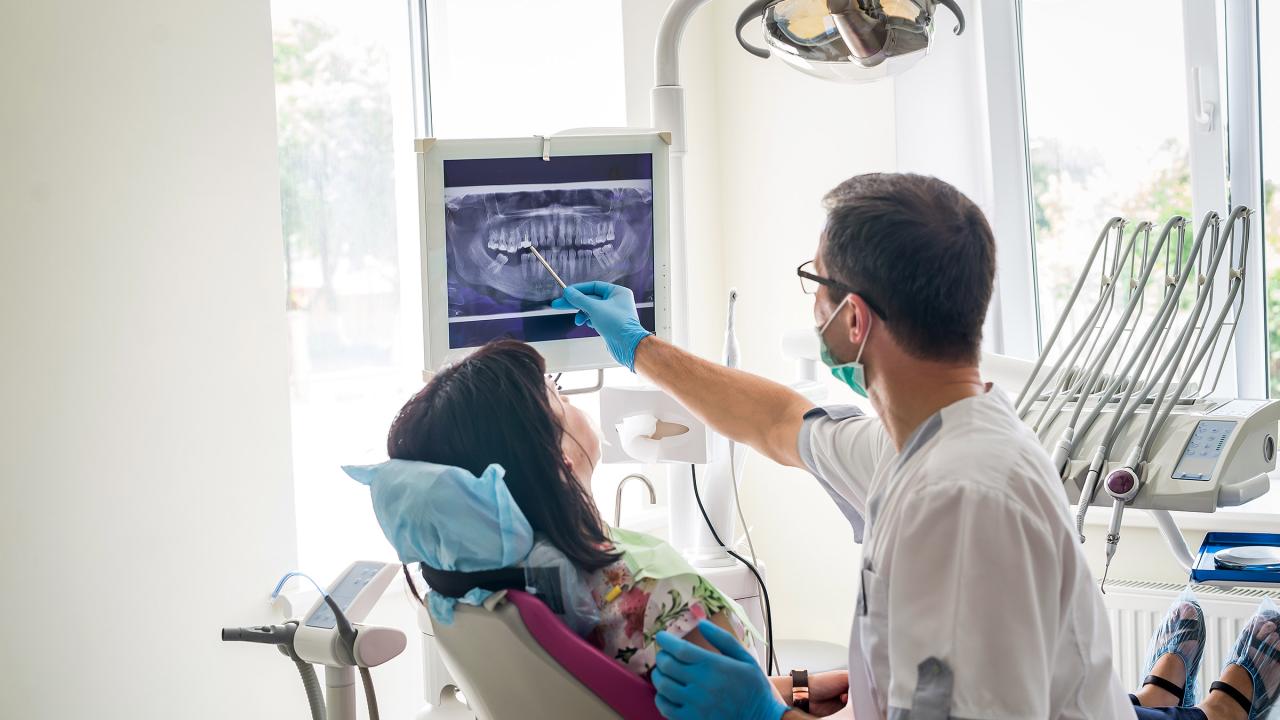Zahnarzt erklärt einer Patientin das Röntgenbild